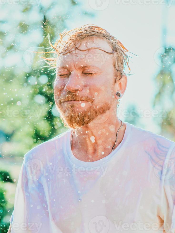 portrait of Caucasian man shaking head with water splashes. Summer fun, party, vacation, emotions, pleasure, relaxation, refreshment concept photo