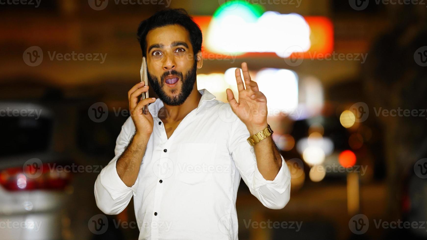 Portrait Of Handsome indian Man Talking On Cellphone night image with excitement photo