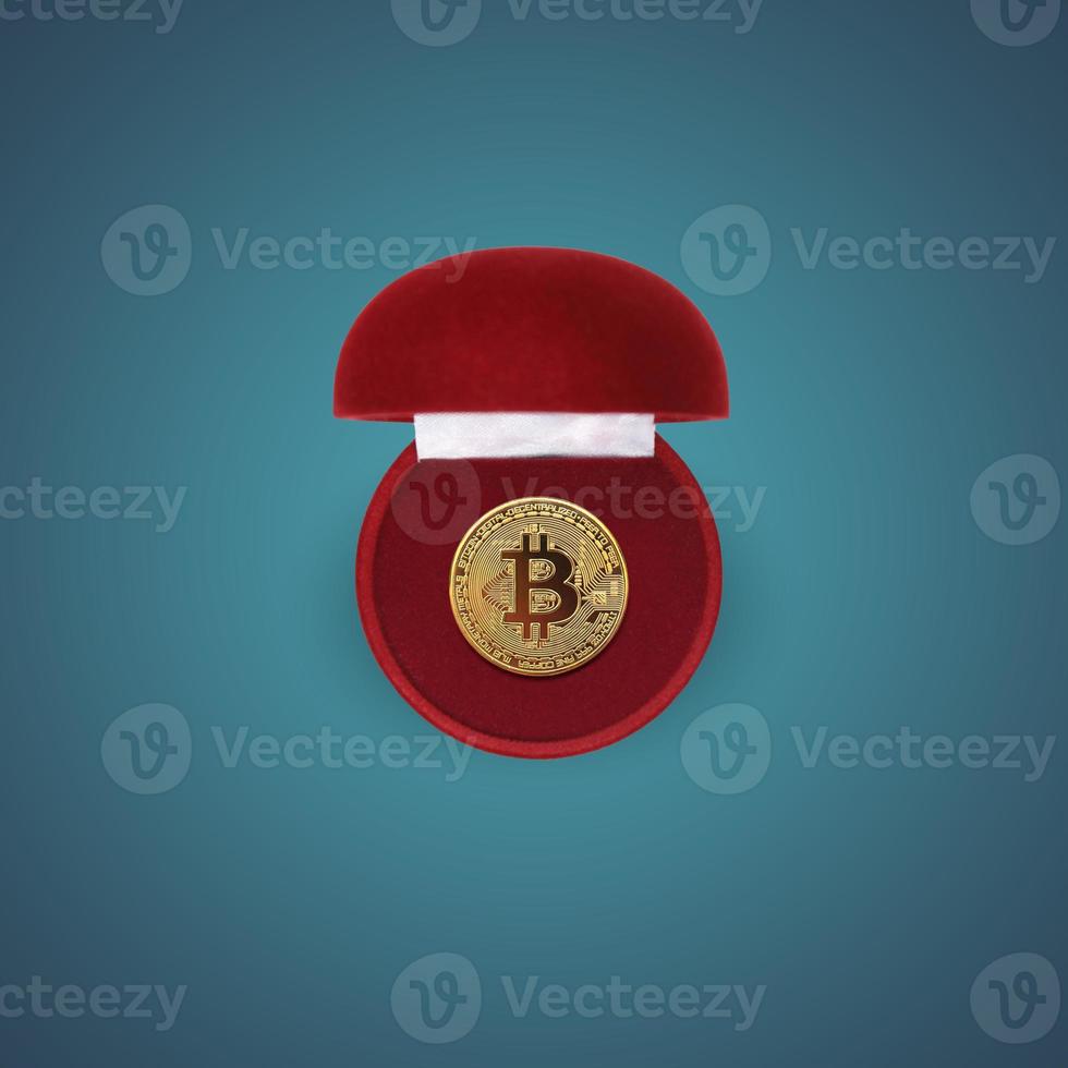Gold bitcoin coin in a red gift box on blue background. Creative concept idea. Cryptocurrency, trading. investment. Flat lay, top view. photo