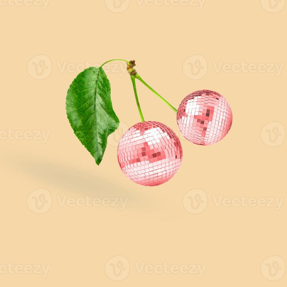 Unusual combination of usual things. Red cherries as a disco balls flying on beige background. Modern design. Copy space. Contemporary art. Collage made out of red cherries and disco balls. photo