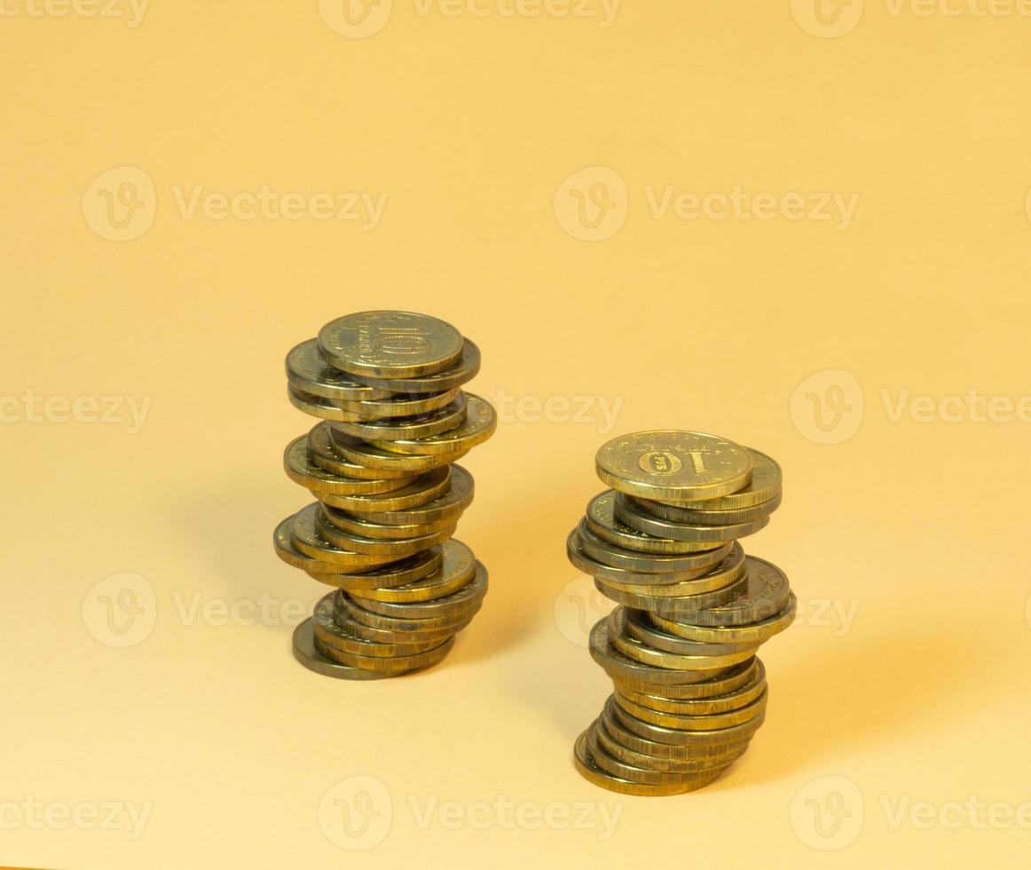 Two turrets made of coins. Money on yellow background photo