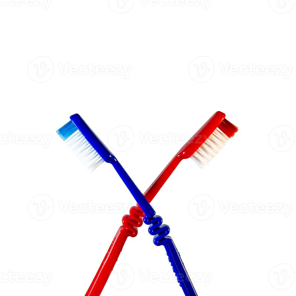 Two toothbrushes crossed on a white background. Blue and red toothbrushes photo