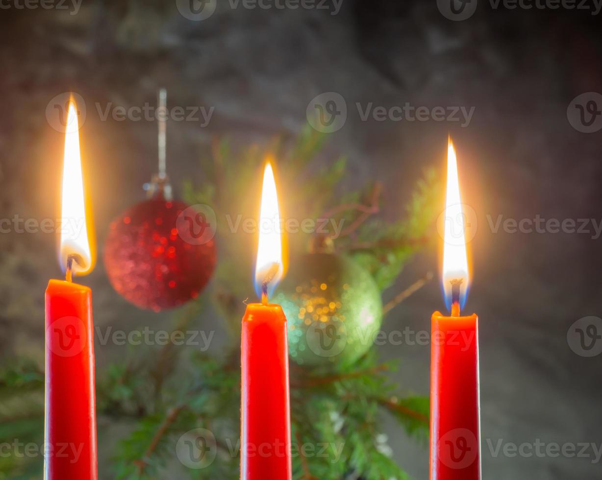 las velas rojas de navidad están ardiendo en el fondo de las ramas de abeto. Decoración navideña. ambiente de año nuevo foto