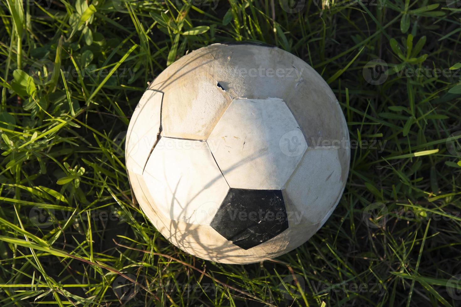 An old soccer ball lies in the grass, close-up photo