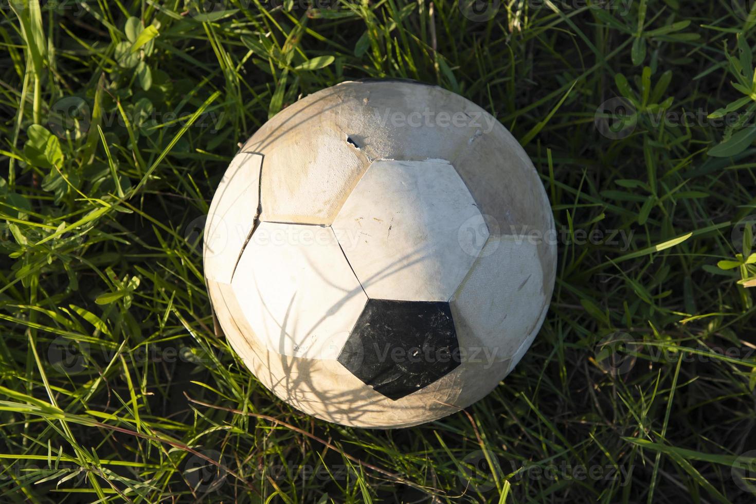 An old soccer ball lies in the grass, close-up photo