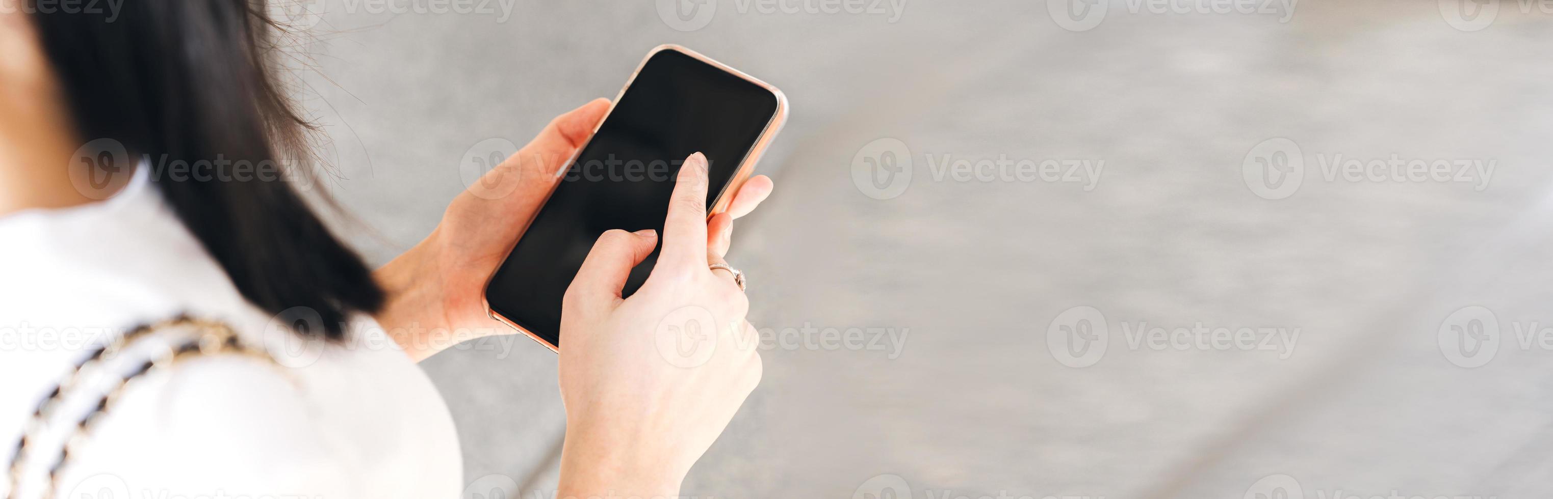 Woman hand holding a smart phone at outdoor and touching text a message chat. photo