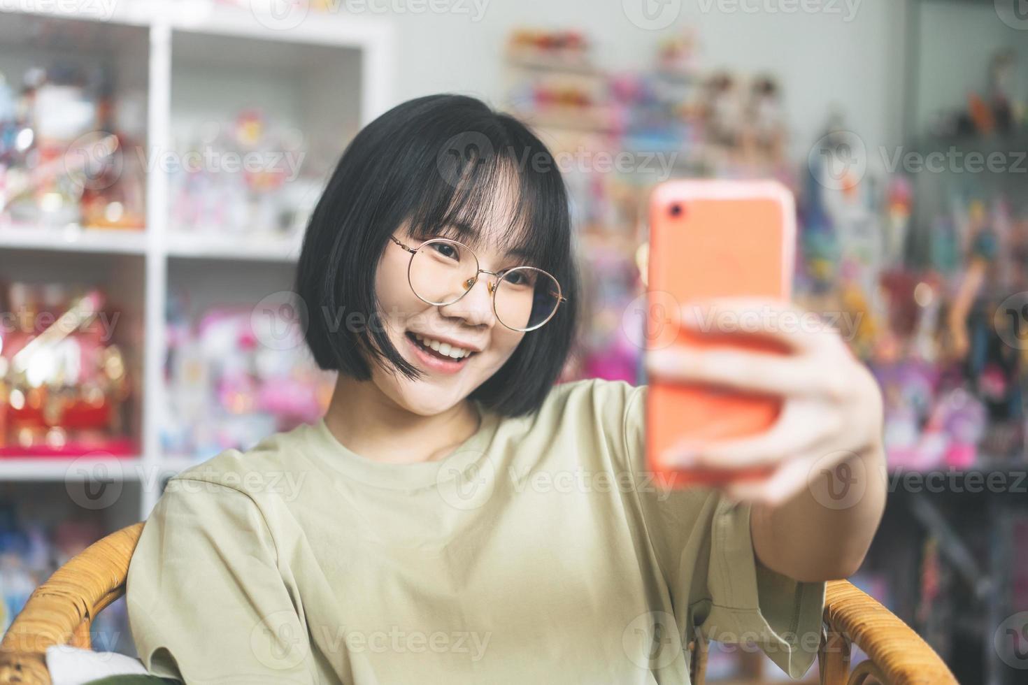 Young adult asian woman using mobile phone for selfie or live social online at home photo