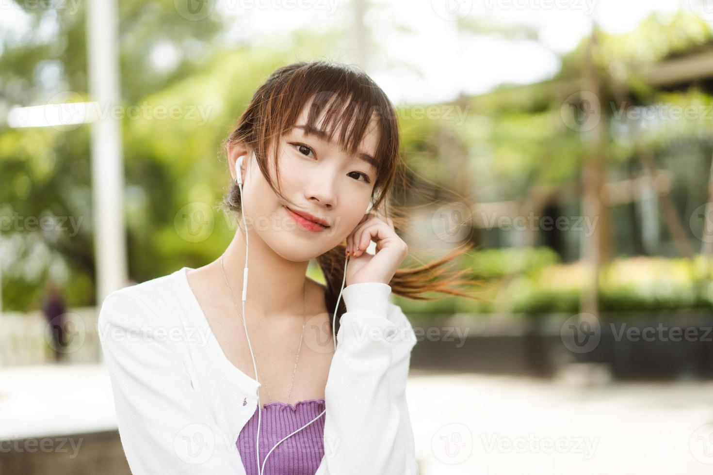 Happy young adult asian woman listening streaming music at outdoor on day. photo