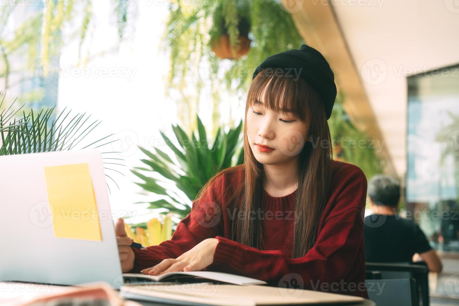 mujer adulta joven estudiante universitaria asiática con computadora portátil para estudiar en el café el día de invierno. foto