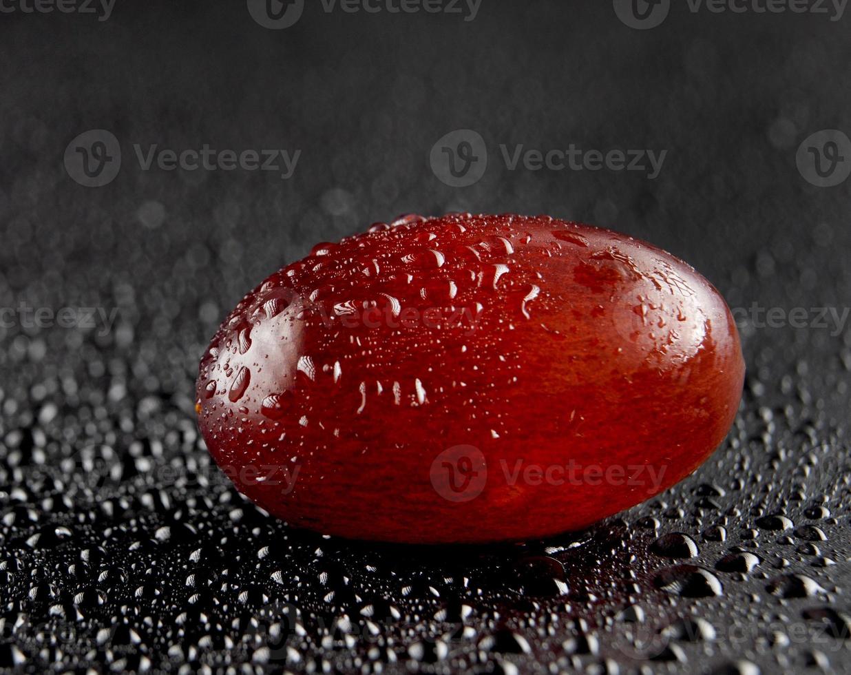 One grape berry on a dark background. Water drops. photo