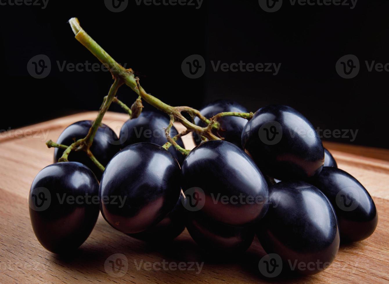 A small bunch of black grapes on a wooden board. photo