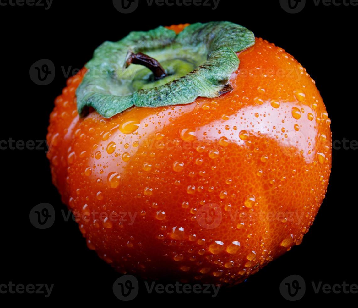 Perfect picture of ripe persimmon with drops of water on the peel. isolated on a black background. photo