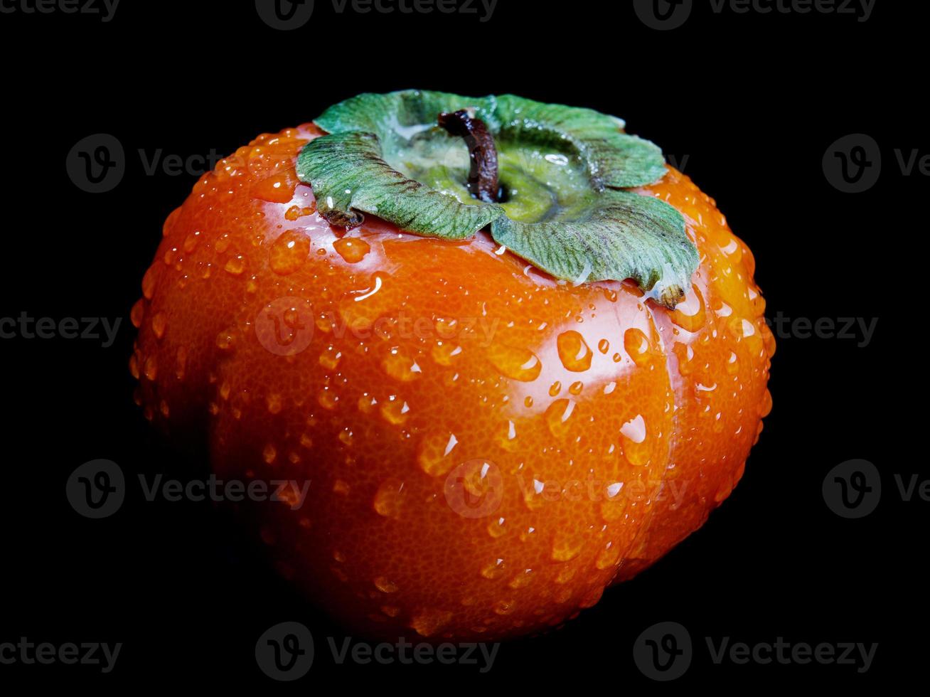 Ripe juicy persimmon is isolated on a black background. photo