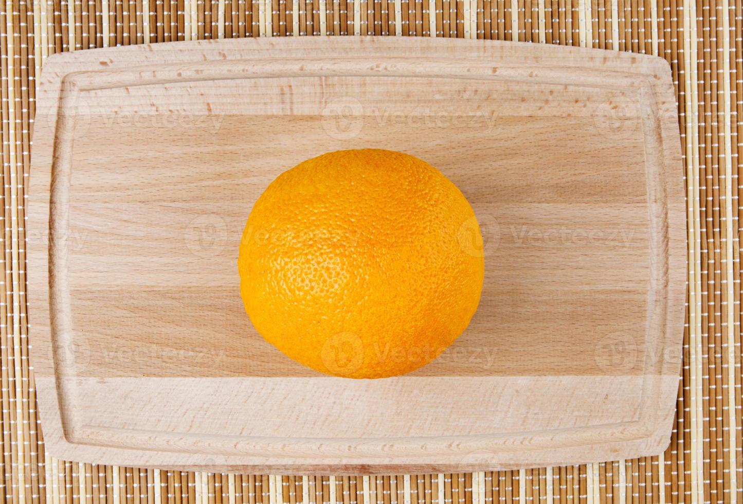 A juicy orange on a wooden cutting board. photo