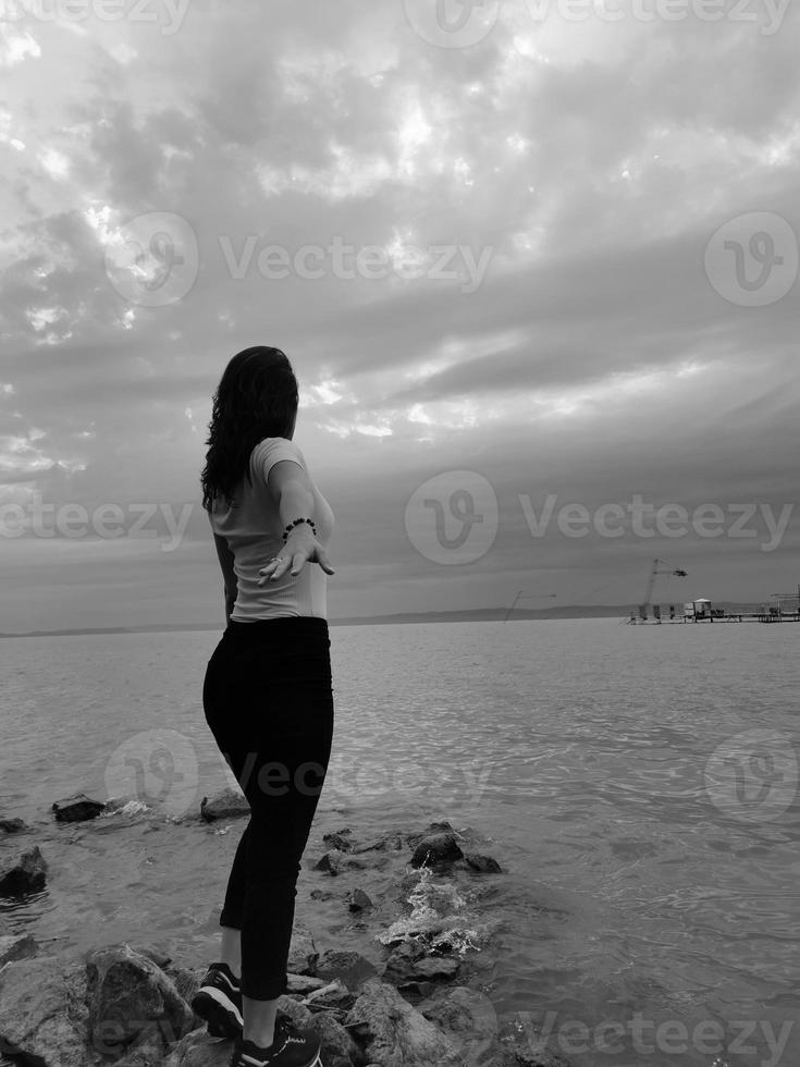 A woman standing next to a body of Balaton photo
