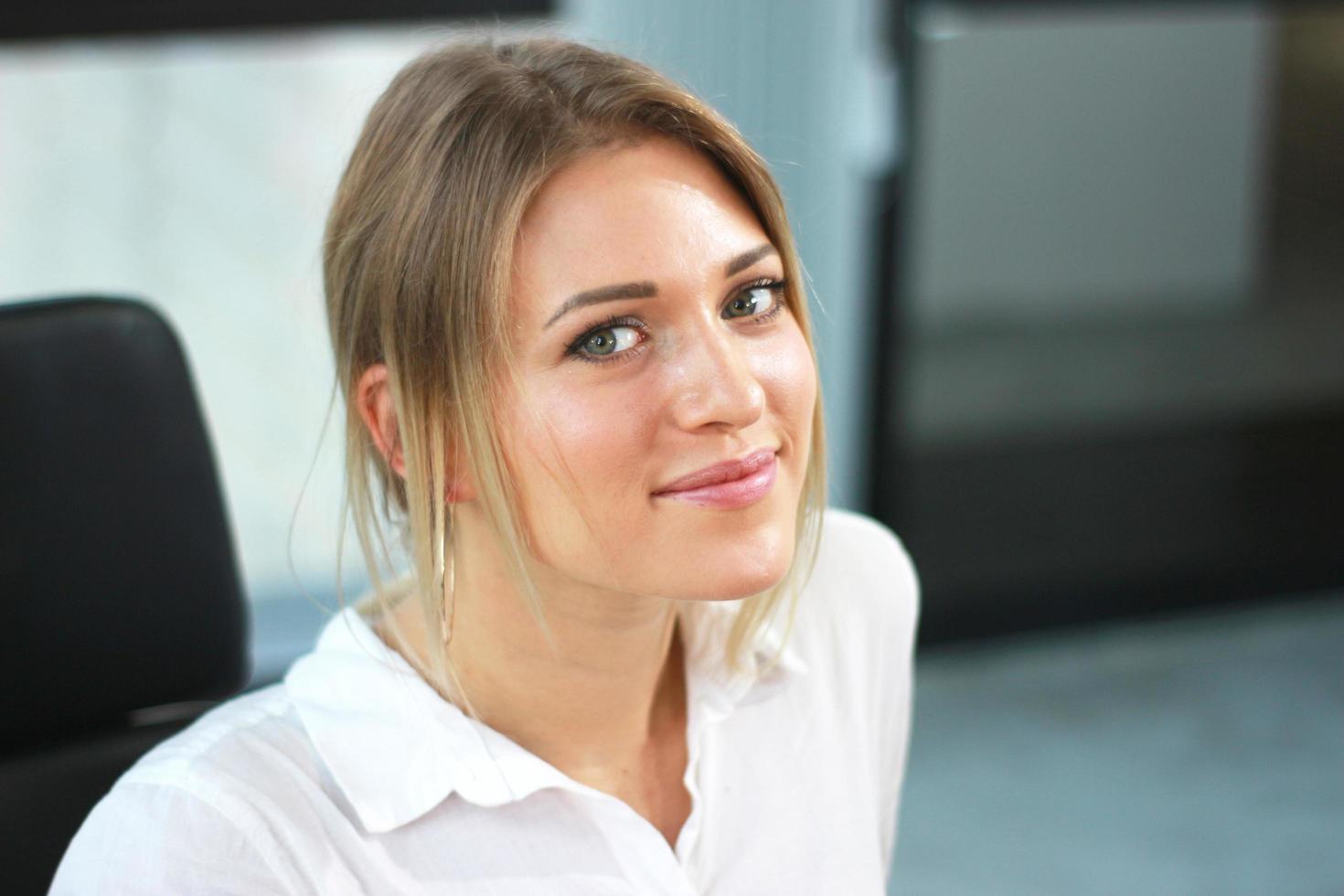 Closeup portrait of cute young businesswoman smiling in modern office building photo