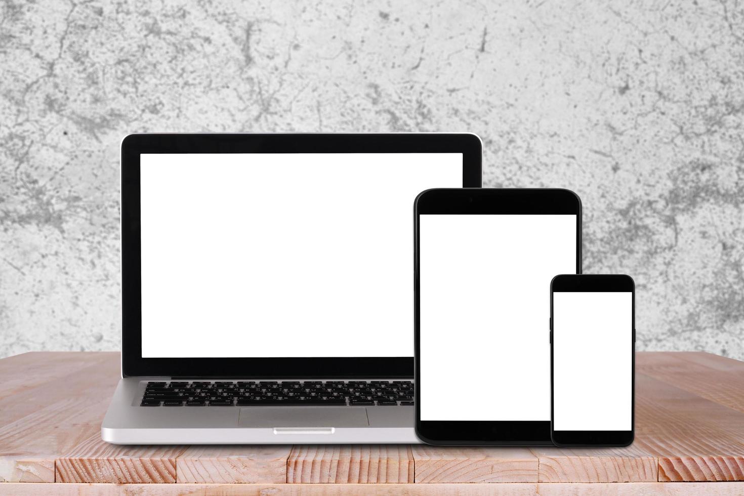 Front view of the laptop, tablet pc, smartphone is on the work table with white concrete background photo