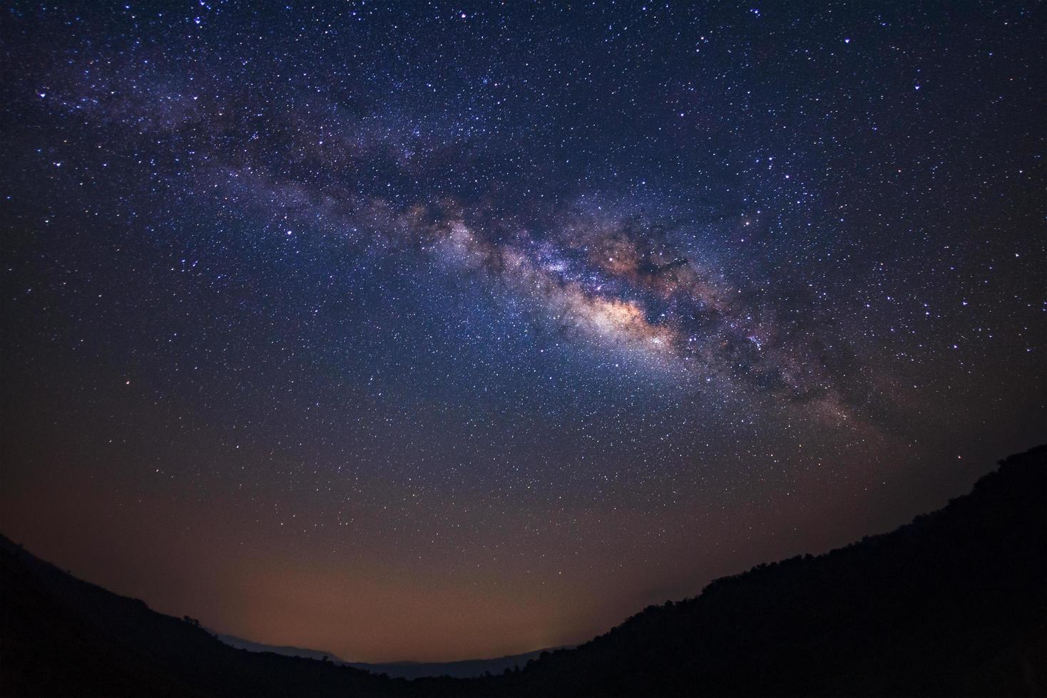 galaxia paisajística de la vía láctea con estrellas y silueta de un hombre feliz de pie, fotografía de larga exposición, con grano. foto