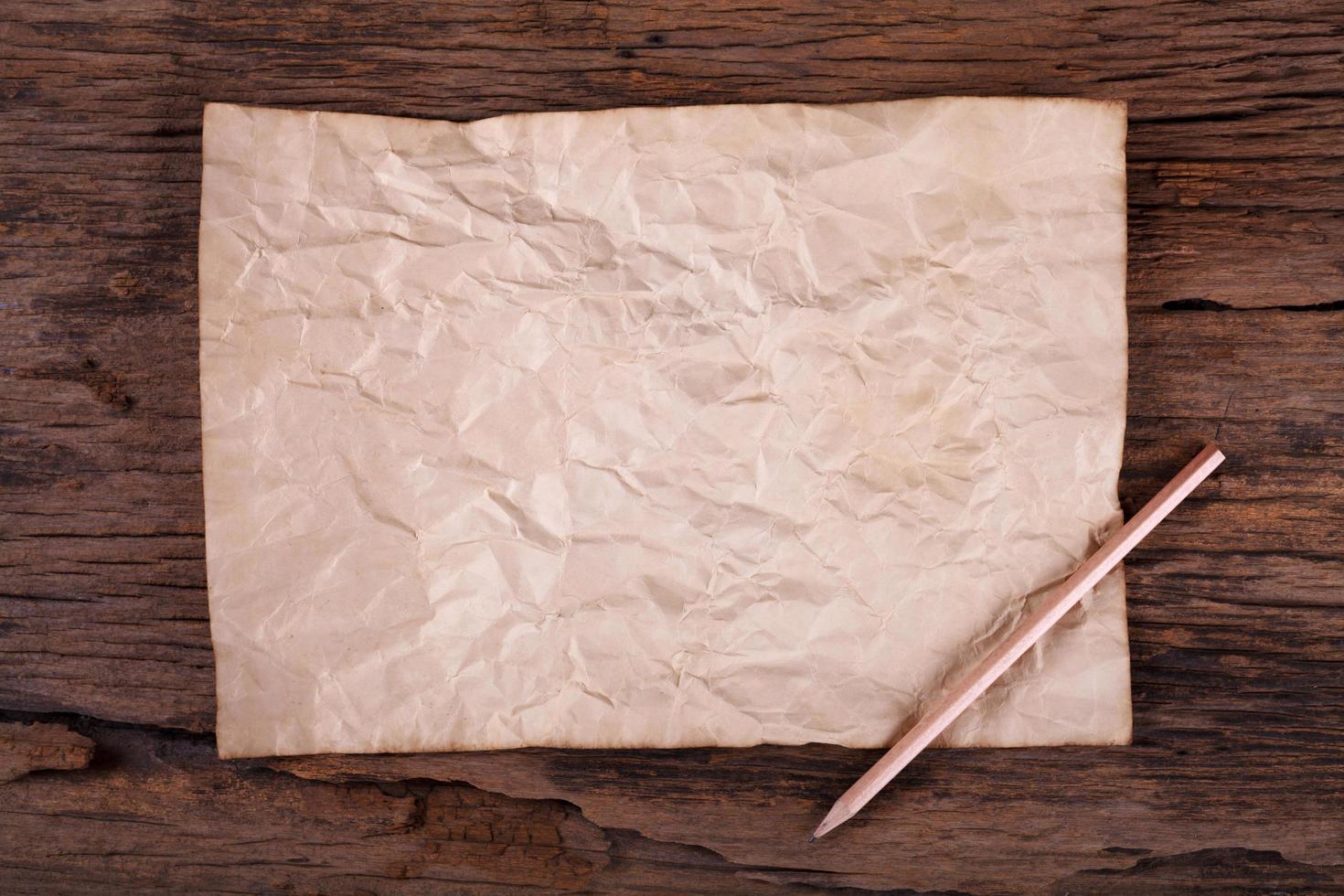 Old paper with pencil on wooden table photo