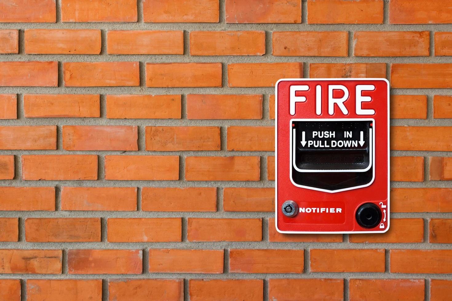 Fire alarm switch on brick wall texture background photo