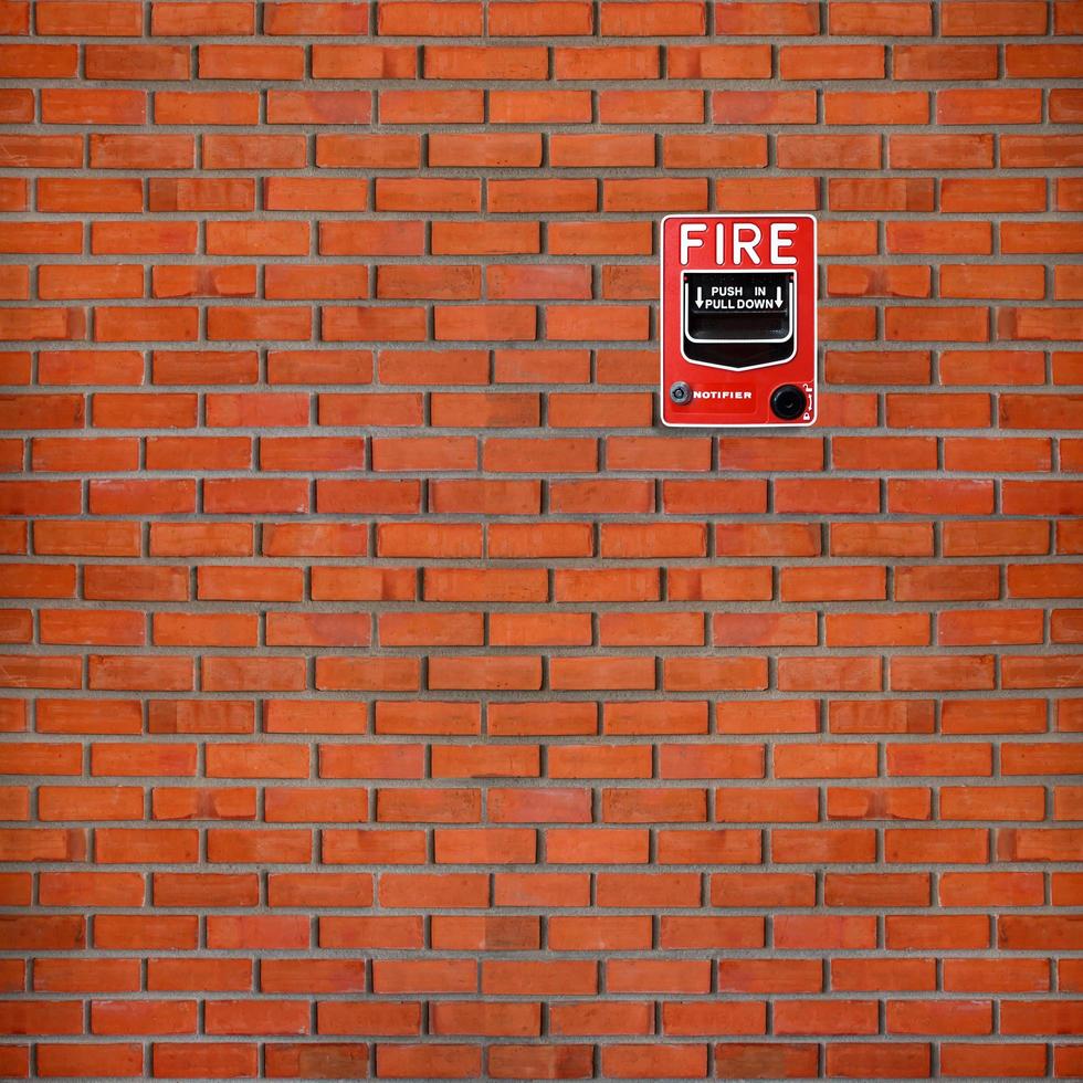 Fire alarm switch on brick wall texture background photo