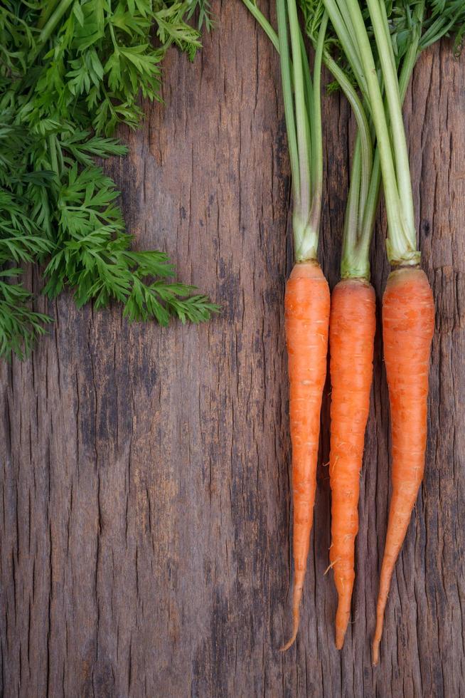 Bunch of fresh carrots with green leaves over wooden background 9812037