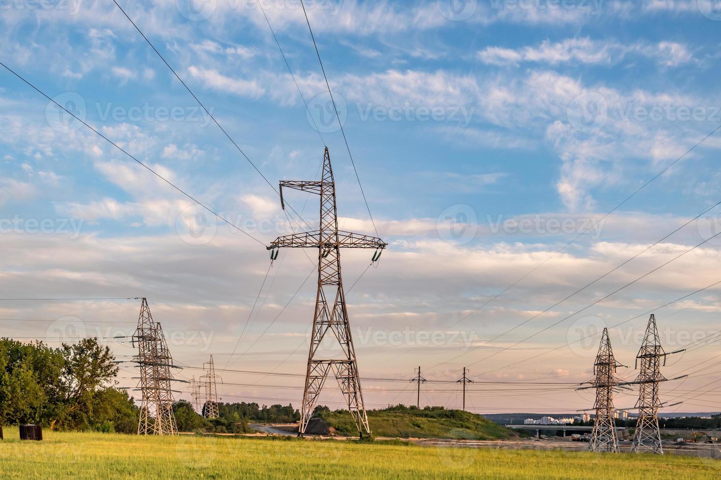 Silhouette of the high voltage electric pylon towers on the background of beautiful evening clouds photo