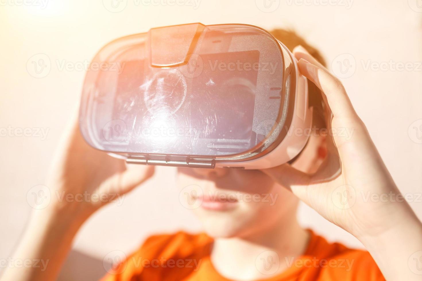 niño con camiseta naranja con gafas de realidad virtual vr ar 360 cartón para teléfono móvil jugando el juego. dispositivo para ver películas para viajes y entretenimiento en el espacio 3d. foto