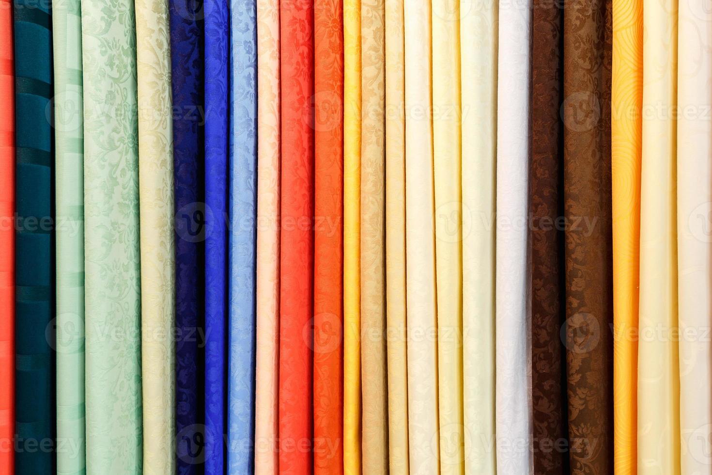 wide selection of different color textile silk fabrics clothes lay in row in drapery store photo