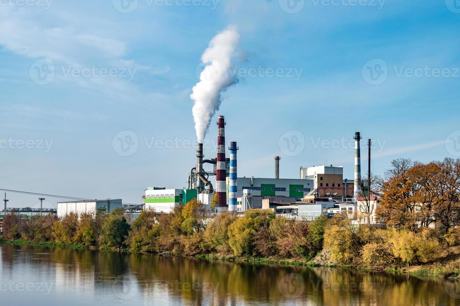 tuberías del aserradero de la planta de la empresa de carpintería cerca del río. concepto de contaminación del aire. paisaje industrial contaminación ambiental residuos de central térmica foto