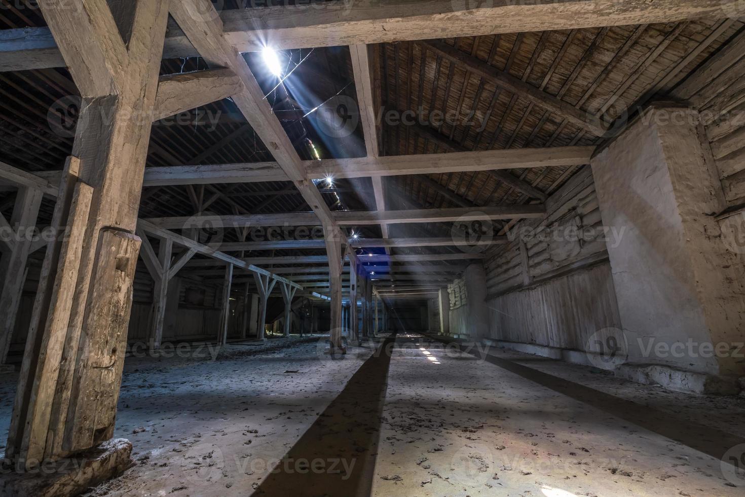 inside dark abandoned ruined wooden decaying hangar with rotting columns photo