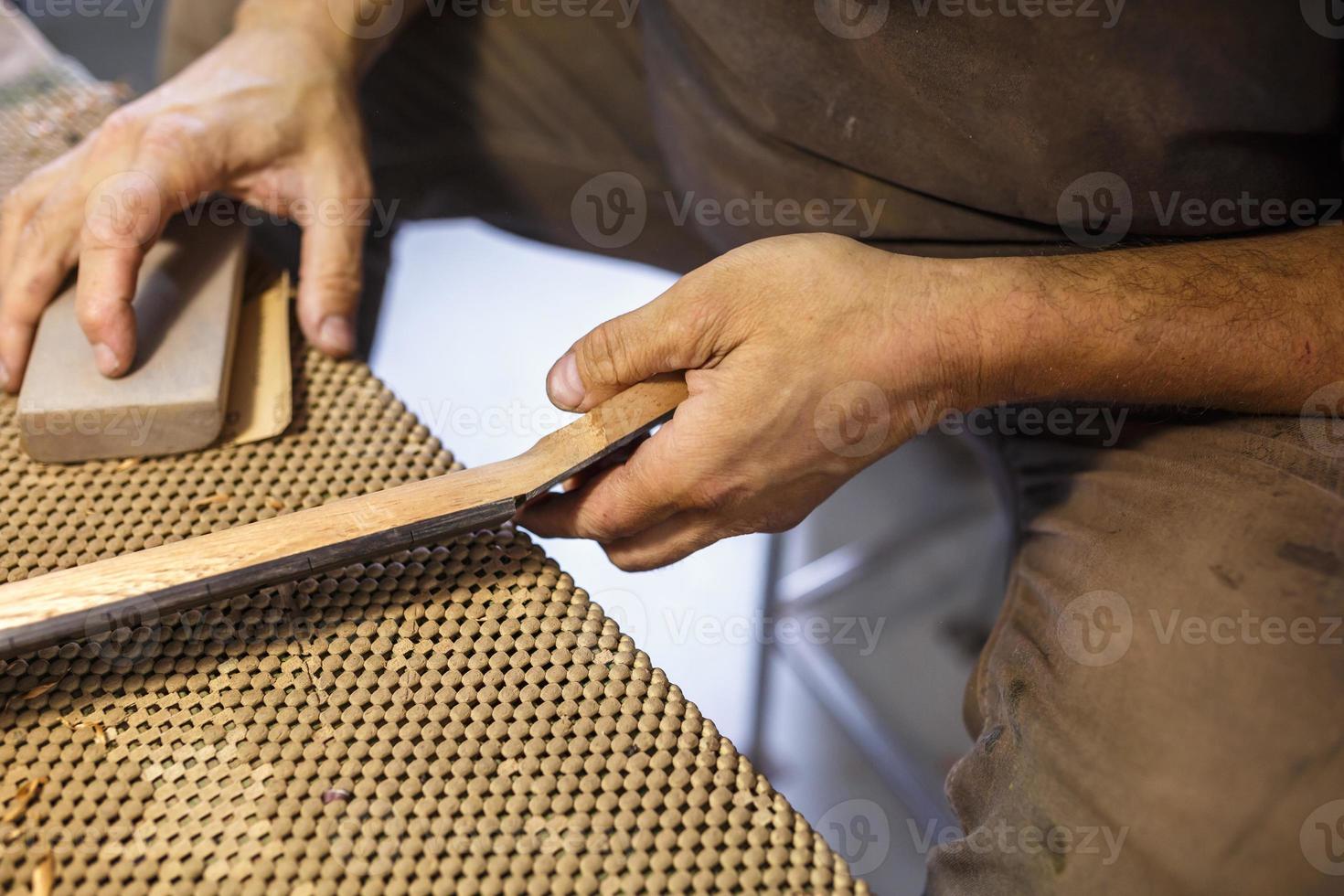 grinding and polishing the guitar wooden neck. hand-made musical instruments photo