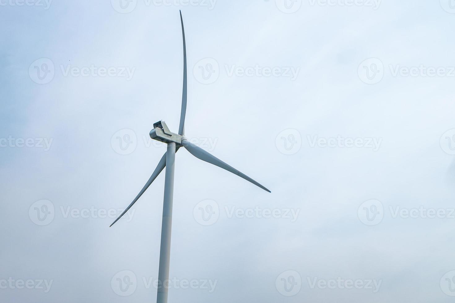 rotating blades of a windmill propeller on blue sky background. Wind power generation. Pure green energy. photo