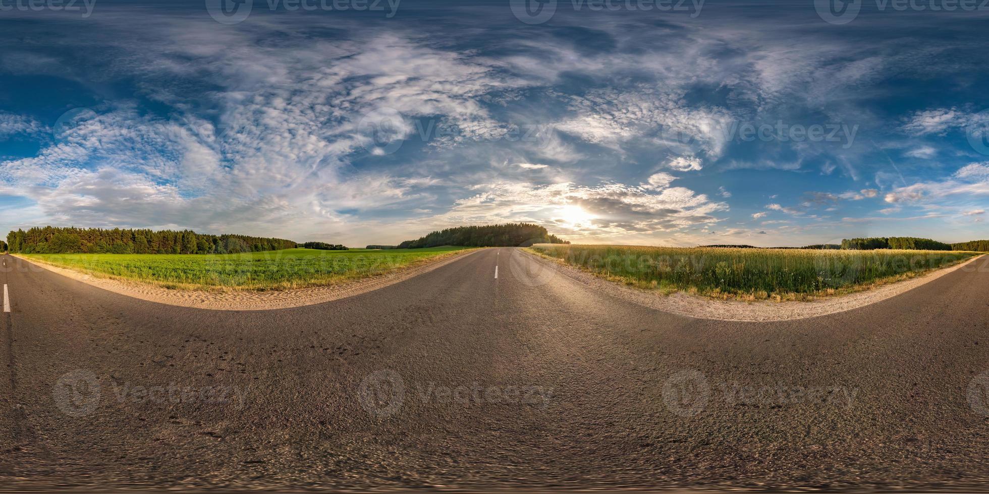 panorama esférico de hdri vista angular de 360 grados en carretera asfaltada entre campos en la puesta de sol de la tarde de verano con nubes impresionantes en proyección equirectangular, contenido de realidad virtual listo vr ar foto