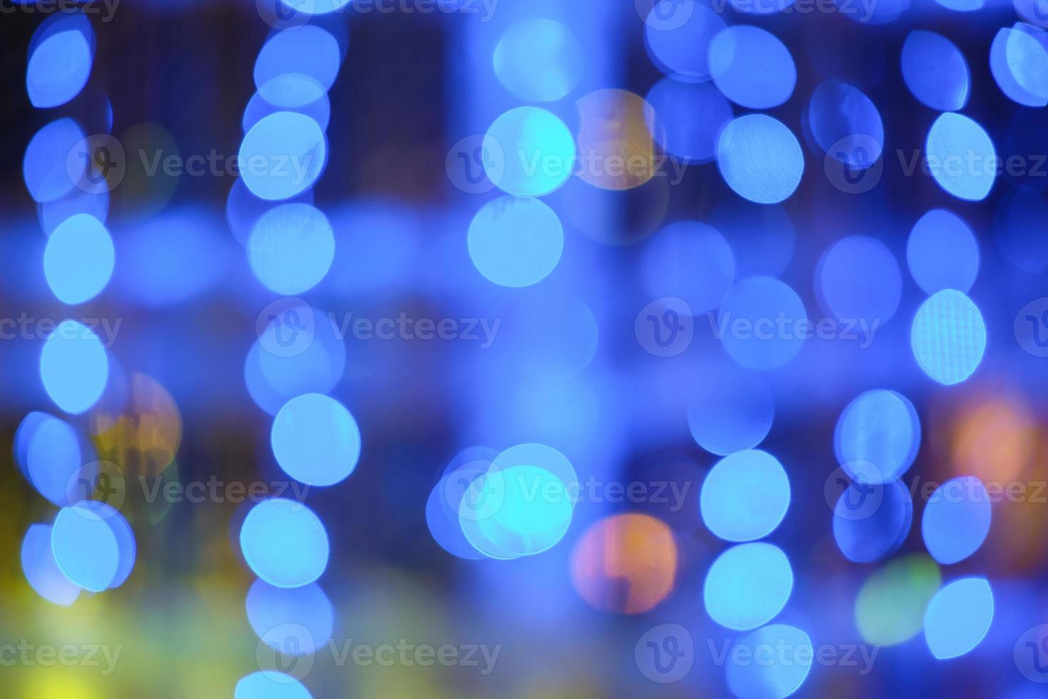 Blurred bokeh colorful lights lanterns, holiday new year lighting on black background Christmas winter glitter shiny light bokeh in rainbow colors. Holiday purple blue pink violet natural texture. photo