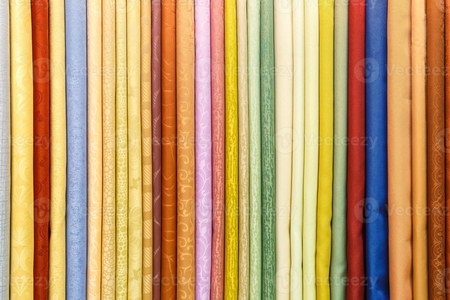 wide selection of different color textile silk fabrics clothes lay in row in drapery store photo