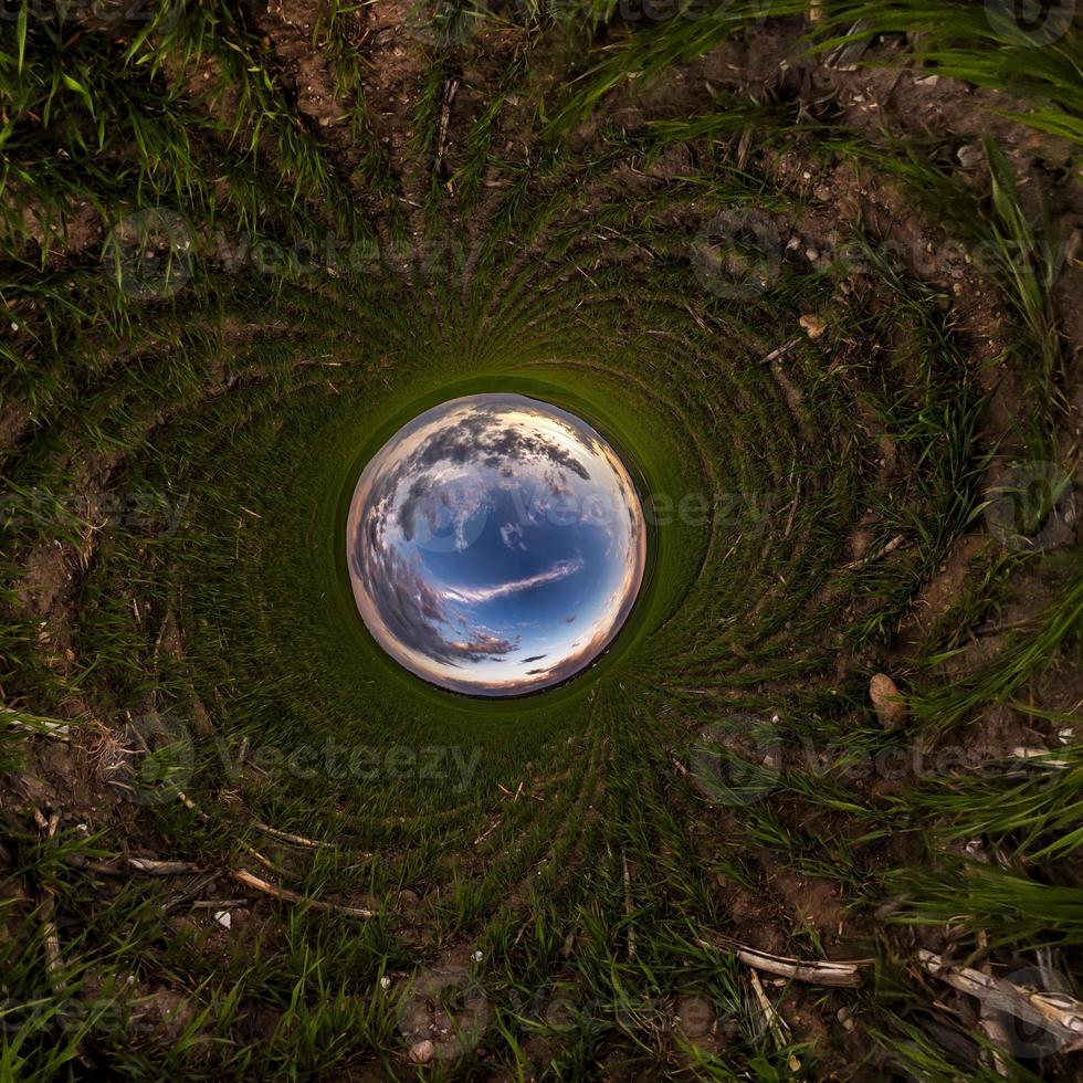 Inversion of blue tiny planet transformation of spherical panorama 360 degrees. Spherical abstract aerial view on field with awesome beautiful clouds. Curvature of space. photo