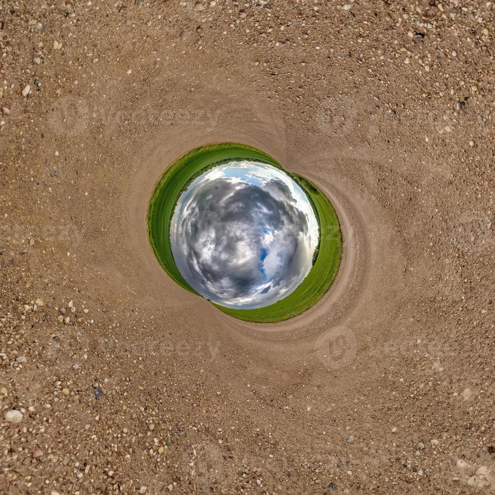 Inversion of blue little planet transformation of spherical panorama 360 degrees. Spherical abstract aerial view on road with awesome beautiful clouds. Curvature of space. photo