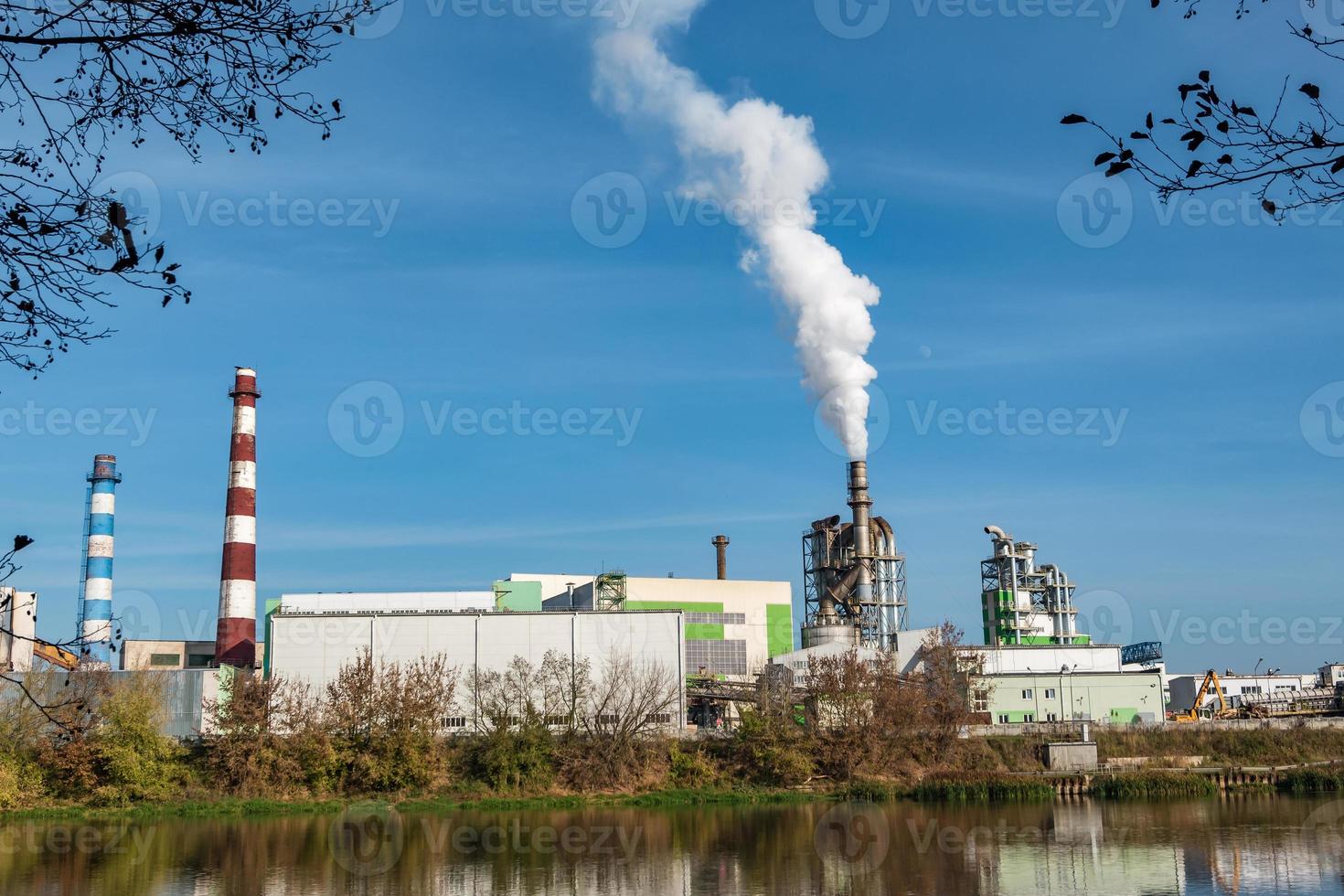pipes of woodworking enterprise plant sawmill near river. Air pollution concept. Industrial landscape environmental pollution waste of thermal power plant photo