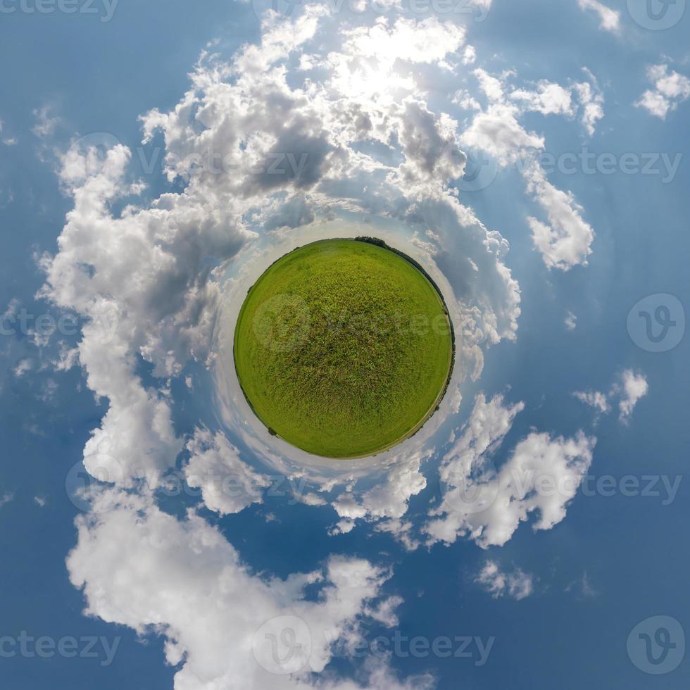 tiny planet in blue sky with beautiful clouds with transformation of spherical panorama 360 degrees. Spherical abstract aerial view. Curvature of space. photo