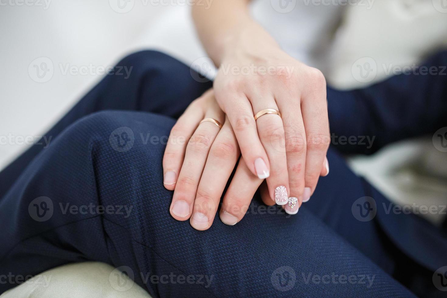 el novio abraza las manos de la novia con anillos en los dedos de los recién casados foto