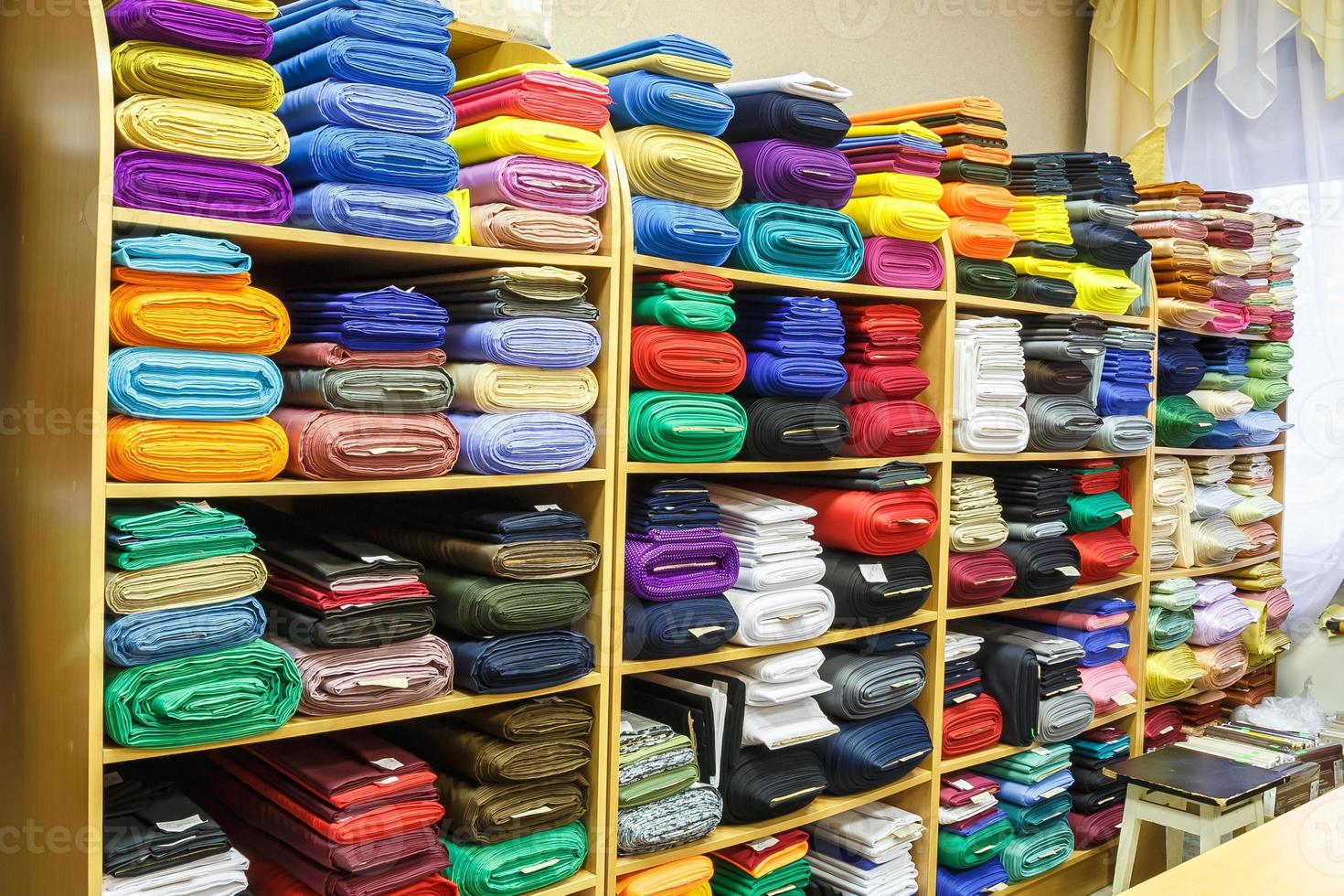 estantes con telas de diferentes colores en la tienda de textiles de élite foto