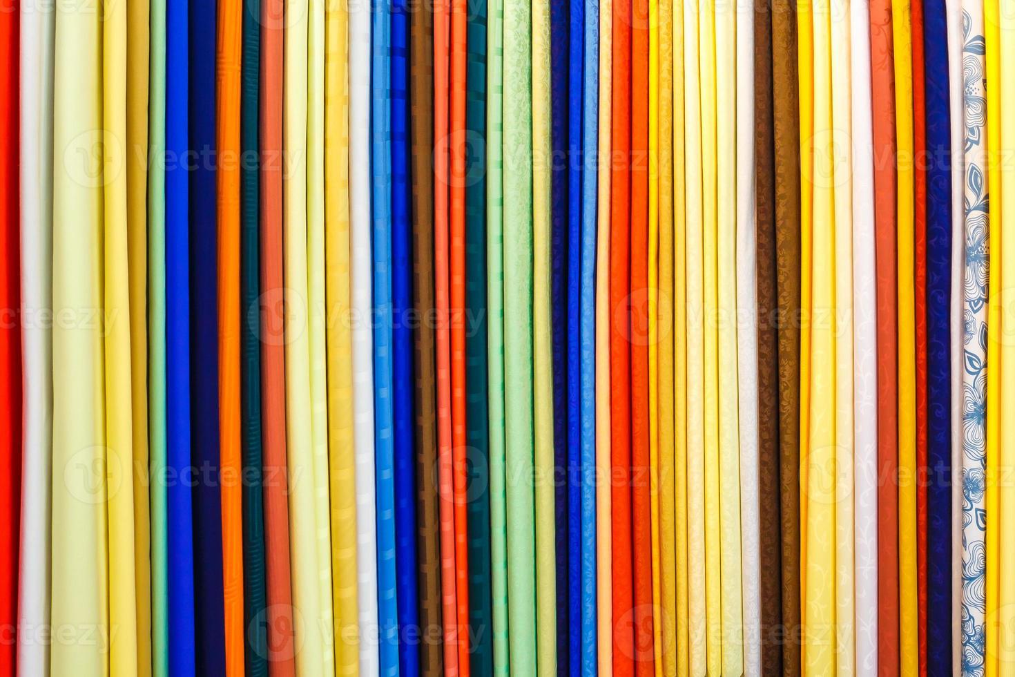 wide selection of different color textile silk fabrics clothes lay in row in drapery store photo