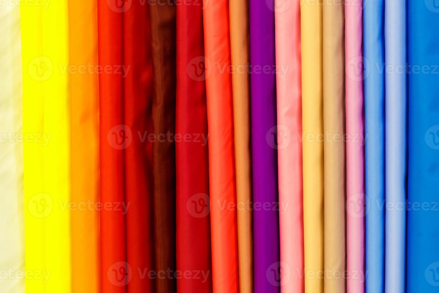 wide selection of different color textile silk fabrics clothes lay in row in drapery store photo