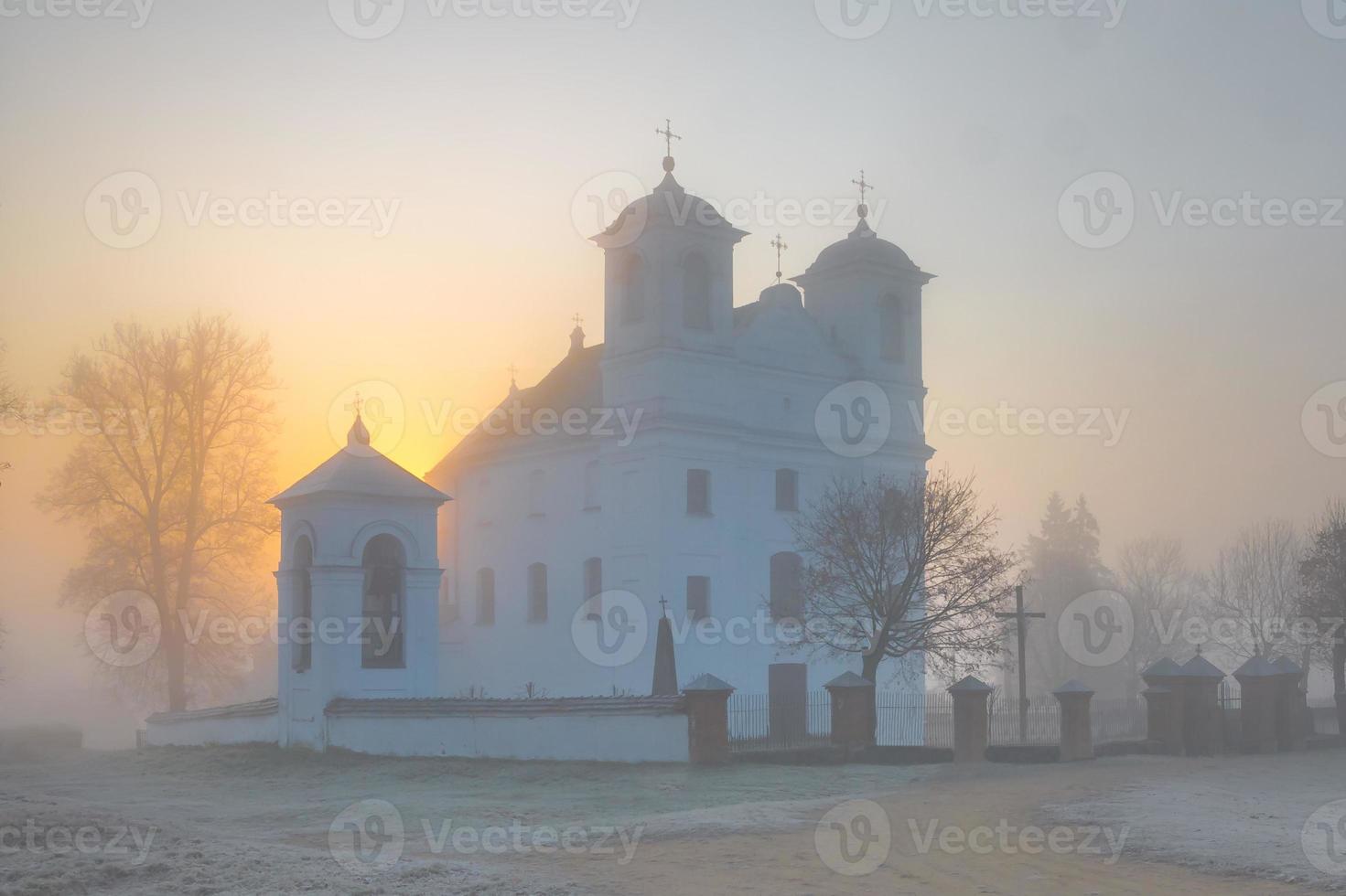 hermosa iglesia católica a principios de la mañana de niebla de otoño foto