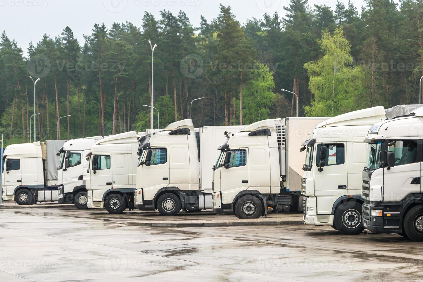 Trucks in a row with containers in the parking lot near forest , Logistic and Transport concept photo