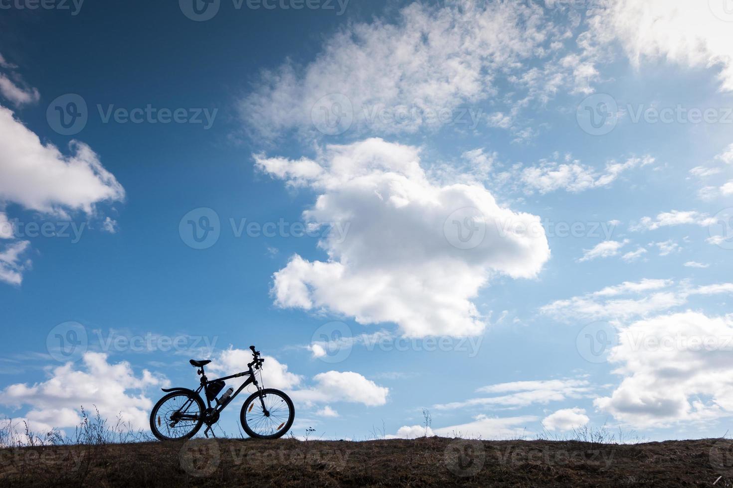 Bike silhouette in blue sky with clouds. symbol of independence and freedom photo