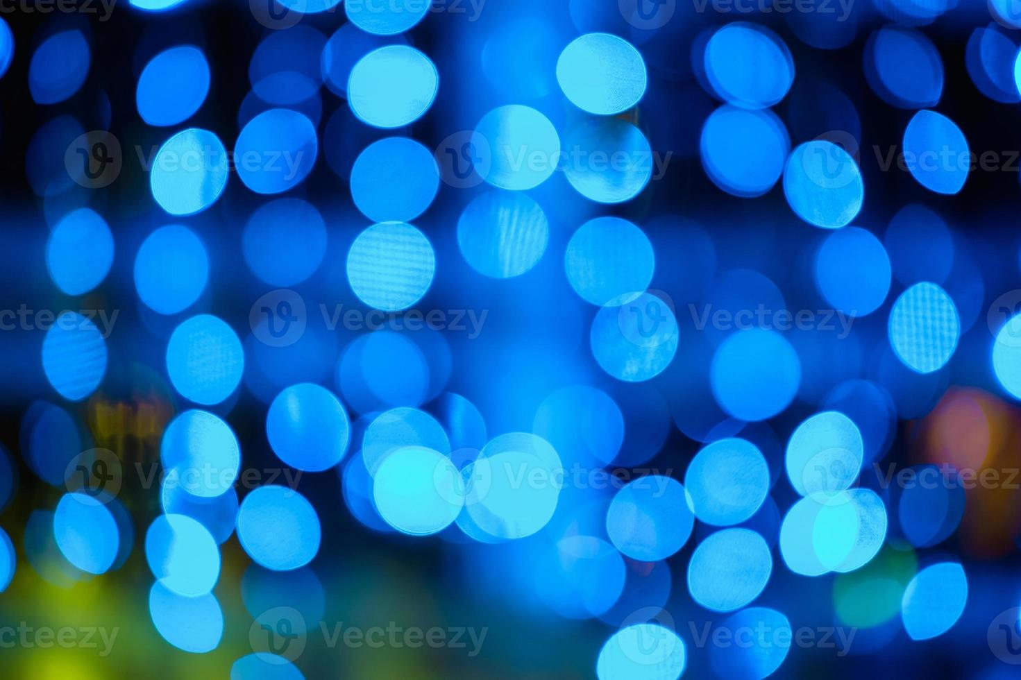 Blurred bokeh colorful lights lanterns, holiday new year lighting on black background Christmas winter glitter shiny light bokeh in rainbow colors. Holiday purple blue pink violet natural texture. photo