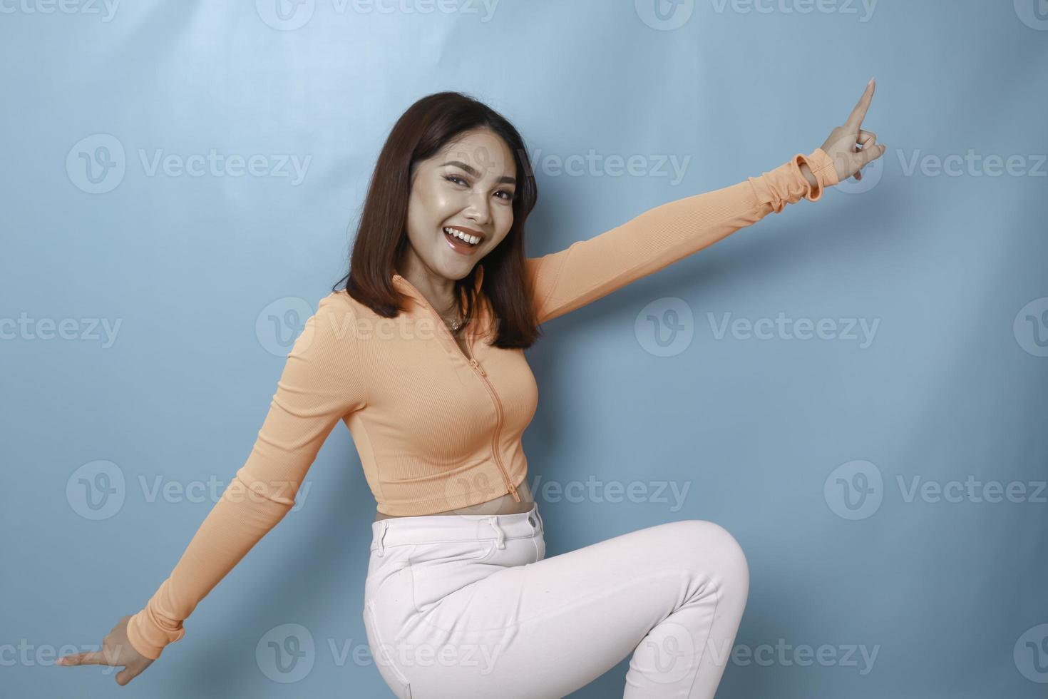 Portrait of Young beautiful Asian woman standing and smiling at the camera, isolated on blue background photo