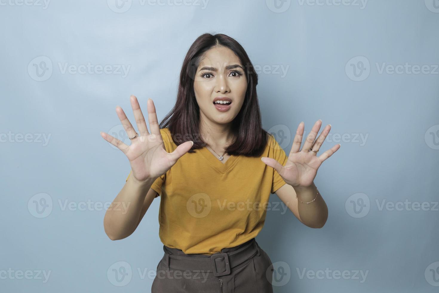 Stop. Concerned Asian woman showing refusal sign, saying no, raise awareness, standing over blue background photo
